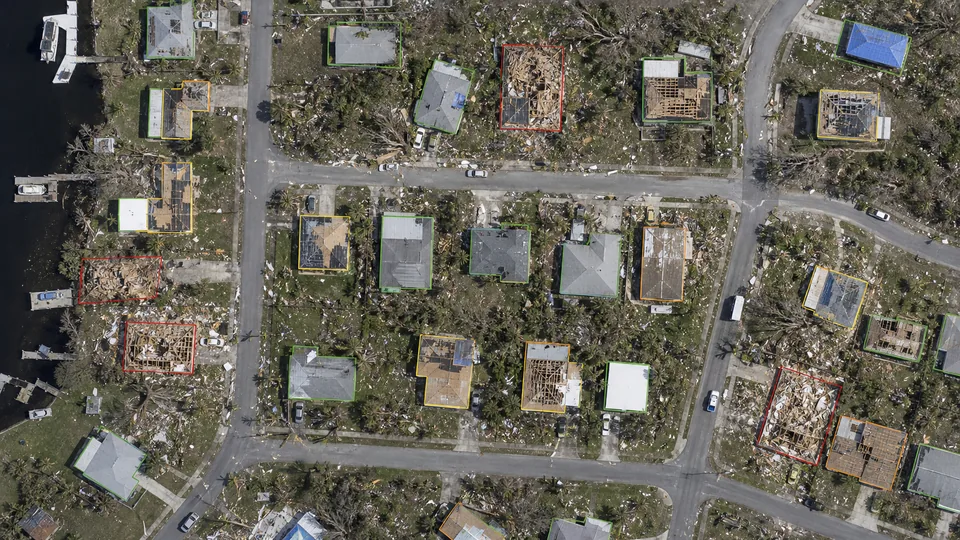 Post-disaster aerial scene with graded building damage outlines